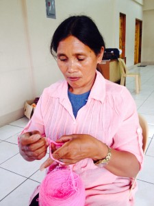 Manang Leonila tries on the new skill she has learned from one of the SLP trainings she has attended. Knitting would help her produce new products which she can sell.